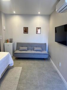 ViVale suítes في أرايال دو كابو: غرفة معيشة مع أريكة زرقاء وتلفزيون بشاشة مسطحة +5 صور