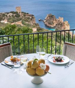 a table with a bowl of food and glasses of wine at Torre Bennistra in Scopello
