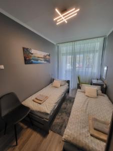 a room with two beds and a chair in it at Elizabet Apartman Szolnok in Szolnok