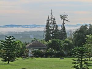 a house in the middle of a field with trees at The Natural Garden Resort in Ban Thap Sai