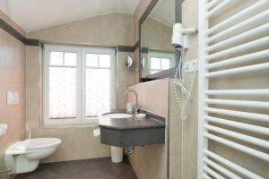 a bathroom with a sink and a toilet and a window at Hotel Sylter Blaumuschel in Westerland +42 photos
