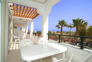 - une table et des chaises blanches sur un balcon donnant sur l'océan dans l'établissement Sagittarius Apartments, à Tigaki
