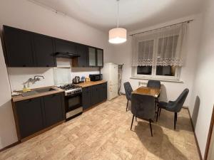une cuisine avec des armoires noires, une table et des chaises dans l'établissement Apartament Zacisze 2, à Przemyśl