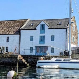 a boat is docked in front of a building at Harbour view retreat with games room in Isle of Whithorn