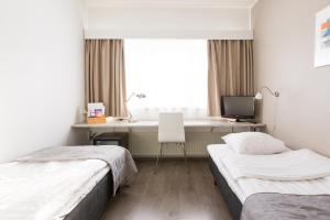 a bedroom with two beds and a desk with a computer at Finlandia Hotel Alba in Jyv&auml;skyl&auml;