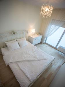 a bedroom with a white bed and a chandelier at Apartment Suvekorter Aida in Pärnu