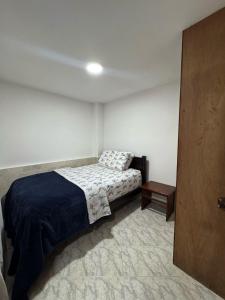 a small bedroom with a bed and a table at Apartamento Edificio Parques Del Trianon in Envigado