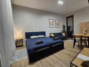 a bedroom with a blue bed and a living room at APARTAMENTY PRUCHNICKA in Jarosław