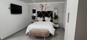 a bedroom with a bed and a ottoman and a television at Entire Self-Catering Apartment in Silverfields in Krugersdorp