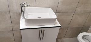 a bathroom with a white sink and a toilet at Entire Self-Catering Apartment in Silverfields in Krugersdorp