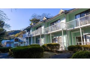a green house with white balconies and bushes at Le Nessa Akazawa - Vacation STAY 16387v in Futo