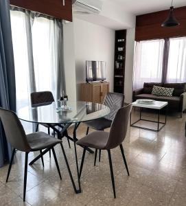 a dining room with a glass table and chairs at Comfortable Engomi Apartment in Yukarı Lakatamya +10 photos