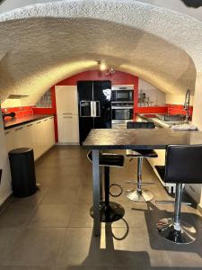 a kitchen with red walls and a counter with stools at La Maison Villageoise in Baix