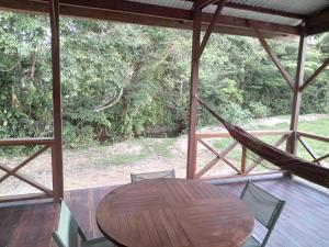 a hammock on a porch with a table and chairs at Palavas la crique in Saint-Laurent du Maroni