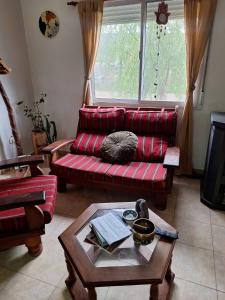 ein Wohnzimmer mit einem roten Sofa und einem Tisch in der Unterkunft Casas Buen Camino y La Magia in Sierra de la Ventana