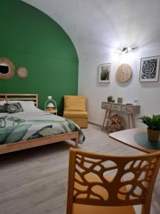 una camera da letto con pareti verdi, un letto e un tavolo di Borghetto Capuana House a Catania