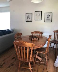a wooden dining room table with four chairs and a couch at Westlake Cottages - Tulip Tree in Wellington