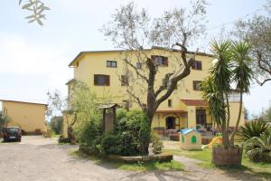 ein gelbes Gebäude mit einem Baum und einem Spielplatz in der Unterkunft Agriturismo Piccolo Paradiso in Piano di Sorrento