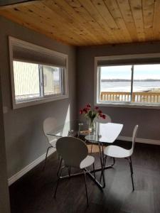 a dining room with a table and chairs and two windows at Westlake Cottage - Wellington Lodge in Wellington
