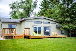 een huis met een terras en stoelen in de tuin bij Westlake Consecon Cottage in Wellington