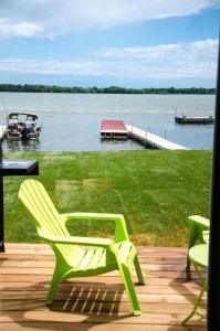 een groene stoel op een dek met een boot in het water bij Westlake Consecon Cottage in Wellington +4 foto's