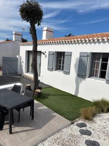 a white house with a table in the yard at Les pieds dans le sable in LʼÉpine