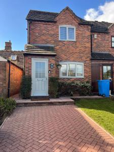 a brick house with a blue door at Bowling Green cottage in Wheaton Aston