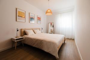 a white bedroom with a large bed and a window at Casa do Sargaço Moledo in Moledo