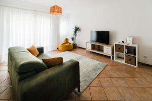 a living room with a couch and a television at Casa do Sargaço Moledo in Moledo
