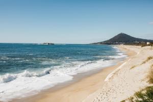 a beach with the ocean and mountains in the background at Casa do Sargaço Moledo in Moledo