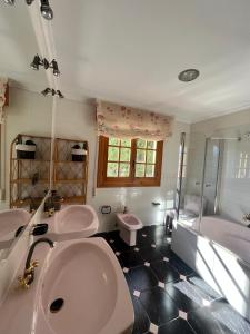 a bathroom with two sinks and a tub and a toilet at El Coronel in Ítrabo