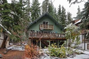 a green house with a deck in the woods at Mt. Hood Chalet in Government Camp