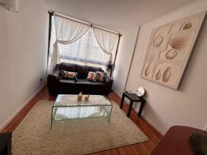 a living room with a black couch and a glass table at Apartment in Santiago-Catedral in Santiago