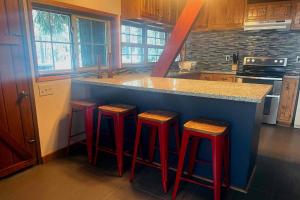 una cocina con una barra con 4 taburetes rojos en Snowball House, en Government Camp 22 fotos más
