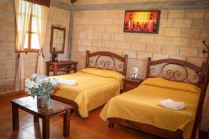 a bedroom with two beds and two tables with flowers at Casa Rural Santa Maria Regla in Huasca de Ocampo