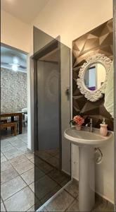 ein Badezimmer mit Waschbecken und Spiegel in der Unterkunft Cantinho aconchegante da Família Moreira na Praia das Palmeiras in Caraguatatuba