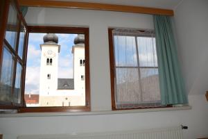 Habitación con 2 ventanas y una torre de reloj. en Kronenwirt, en Gurk