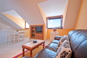 a living room with a leather couch and a table at Apartamentos Casa Paulino in Taramundi