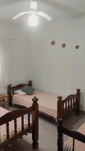 a bedroom with two beds and a ceiling fan at Refúgio próximo as praias de Massaguaçu e Mococa in Caraguatatuba