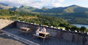 dos personas sentadas en una mesa sobre una pared en Lodge Dinorwig en Llanberis