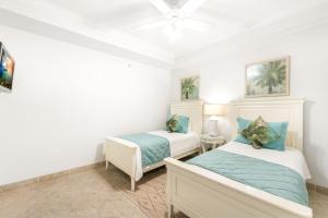 zwei Betten in einem Zimmer mit weißen Wänden und einer Decke in der Unterkunft South Bay Beach Club #6 - 2 Bedroom 2 Bathroom Unit in George Town