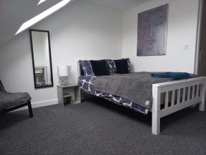 a bedroom with a bed and a mirror and a chair at Large 6 Bed 6 Bathroom House - Ideal For Families, Large Groups, Contractors & Business Travellers in Watford
