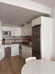 a kitchen with white cabinets and a black refrigerator at Arminda in Arguineguín