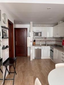 a kitchen with white cabinets and a black table and a table at Arminda in Arguineguín