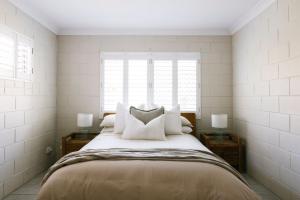 Merduka Sands 4 - Cozy charming cottage في Brooms Head: غرفة نوم بسرير كبير مع مصباحين