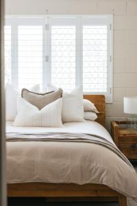 Merduka Sands 4 - Cozy charming cottage في Brooms Head: غرفة نوم بسرير كبير مع وسائد بيضاء