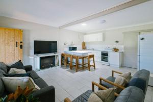 Merduka Sands 4 - Cozy charming cottage في Brooms Head: غرفة معيشة مع أريكة ومطبخ +22 صورة