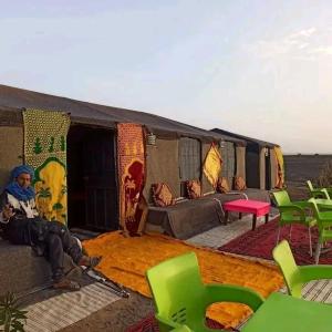 a woman sitting on a couch in front of a tent at chez zakaria luxury tent camp merzouga in Erfoud