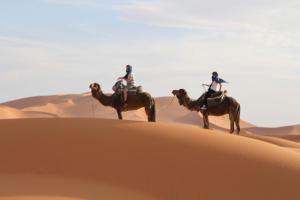two people riding on camels in the desert at chez zakaria luxury tent camp merzouga in Erfoud +8 photos
