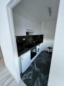 una cucina con armadi bianchi e pavimento in marmo nero di Charmant T2 Haut Standing a Saint-Louis Altre 5 foto